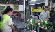 In this picture taken on July 3, 2017 workers manipulate a machine to make car interior pieces for a major European car maker in the American Industrial Park in Shenyang. AFP / Nicolas Asfouri
