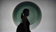 A visitor walks past a backlit photo of a Ru Guanyao brush washer bowl from China's Song Dynasty before its record breaking sale at the Sotheby's Chinese Works of Art Autumn Sales in Hong Kong on October 3, 2017. AFP / Anthony WALLACE