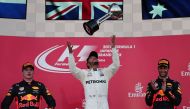 Mercedes' British driver Lewis Hamilton (C) throws his winner's trophy as second placed Red Bull's Dutch driver Max Verstappen (L) and Red Bull's Australian driver Daniel Ricciardo (R) look on from the podium in the Formula One Japanese Grand Prix at Suzu