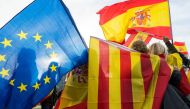 Women hold Spanish, Catalan and European flags during a demonstration against Catalonia's independence in front of the European Parliament building in Strasbourg, eastern France, on October 24, 2017. AFP / PATRICK HERTZOG
