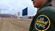 US Border Patrol officer Tekae Michael stands near prototypes of US President Donald Trump's proposed border wall on November 1, 2017 in San Diego, California. AFP / Frederic J Brown