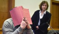 German former male nurse Niels Hoegel hiding his face behind a folder as he waits next to his lawyer Ulrike Baumann (R) for the opening of another session of his trial at court in Oldenburg, northwestern Germany. File photo taken on February 26, 2015. (AF