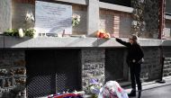 A woman lays a bunch of flowers near a plaque commemorating the victims of a shooting at La Belle Equipe cafe - restaurant during ceremonies across Paris marking the second anniversary of the terror attacks of November 2015 in which 130 people were killed