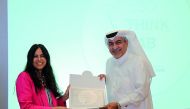 A QFC official receives the certificate from ILO represenatative.
