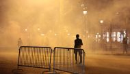 A demonstrator, standing through the smoke from tear gas, walks on the Champs-Elysees avenue in Paris, during a march against 
