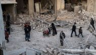 Syrians walk through the rubble down a street filled with destroyed buildings, in the aftermath of reported bombardment by government forces in the rebel-held besieged town of Arbin, in the Eastern Ghouta region on the outskirts of Damascus, during an air