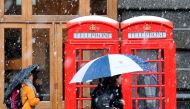 Pedestrians walk as snow falls over central London on December 10, 2017. AFP / DANIEL SORABJI
