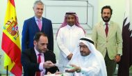 Abdul Aziz Hamad Al Dulaimi (sitting right), President of Gulf Petroleum; and Juan Carlos Santiago (sitting left), GM and COO of AgroQatar; exchanging the documents, after the signing ceremony,  as Ignacio Escobar (standing left) Ambassador of Spain;  Kha