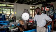 File photo of Ghanaian artist Joseph Awuah-Darko working on a clock, the pieces of which were found at Agbogloshie dumpsite, at his workshop at Ashesi University College where he studies, outside Accra on November 29, 2017. / AFP / CRISTINA ALDEHUELA