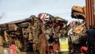Emergency workers stand near the wreckage of a bus and a lorry that crashed in a head-on collision, killing thirty people, at the accident scene near Nakuru, Kenya, on December 31, 2017. / AFP.