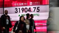 Pedestrians walk past stocks display board after the Hang Seng Index leapt 1.81 percent, or 565.88 points, to close at 31,904.75 in Hong Kong on January 16, 2018. AFP / Anthony WALLACE
