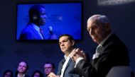 Greek Prime Minister Alexis Tsipras (C) and Organization for Migration (IOM) Director-General William Lacy Swing listen a refugee seen on TV screen behind during a session on mass migration across the Mediterranean during the annual World Economic Forum (