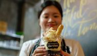 This photo taken on January 24, 2018 shows a staff member holding up a cup of durian flavoured ice cream at Mao Shan Wang café in the Chinatown district of Singapore. AFP / Nicholas YEO
