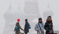 People walk along Red square with St. Basil cathedral seen in the background during snowfall in central Moscow on February 3, 2018. / AFP / Yuri KADOBNOV