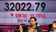 Pedestrians walk past a stocks display board showing the Hang Seng Index at 32022.79, down 1.78 percent, after closing for lunch in Hong Kong on February 5, 2018. AFP / Anthony Wallace 