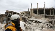Forty-five-year-old Samir Salim (L), who along with his three brothers are members of the White Helmets rescue forces, looks out at destroyed buildings in the town of Medeira in Syria's rebel-held Eastern Ghouta area on February 12, 2018.   AFP / ABDULMON