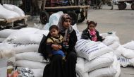 A Palestinian woman sits with a child after receiving food supplies from the United Nations' offices at the United Nations' offices in the Khan Yunis refugee camp in the southern Gaza Strip on February 11, 2018.  AFP / Said Khatib