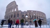 Tourists visit the ancient Colosseum during a snowfall in Rome on February 26, 2018. / AFP / Vincenzo PINTO