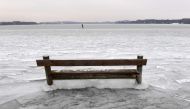 A woman ice skates behind a bench caught in the ice on the frozen Woerthsee lake on March 1, 2018 near the Bavarian village of Inning, southern Germany, as temperatures fell under minus eight degrees celsius. AFP / Christof STACHE

