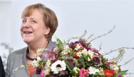 (FILES) This file photo taken on February 9, 2018 shows German Chancellor Angela Merkel holding a flower bouquet given to her by the President of the German Horticultural Association in the chancellery in Berlin.  AFP / John MACDOUGALL
