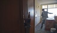 This photograph taken on March 7, 2018 shows an Afghan painter working inside a room with a damaged door at the Intercontinental Hotel in Kabul. AFP / SHAH MARAI 