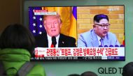 People watch a television news report showing pictures of US President Donald Trump (L) and North Korean leader Kim Jong Un at a railway station in Seoul on March 9, 2018. / AFP / Jung Yeon-je 