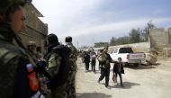 Russian and Syrian soldiers stand guard as Syrians from rebel-held Eastern Ghouta arrive at the regime-held checkpoint in Adra, on the northeastern outskirts of Damascus, after escaping the enclave through a corridor opened by the government forces on Mar