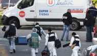 French forensic officers carry away material after a man took hostages at the Super U supermarket in the town of Trebes, southern France on March 23, 2018. AFP / Pascal Pavani