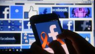 A cellphone and a computer screen display the logo of the social networking site Facebook on March 22, 2018, in Asuncion. AFP / NORBERTO DUARTE