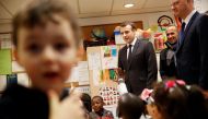 French President Emmanuel Macron (C) and French Education Minister Jean-Michel Blanquer (R) speak with pre-school children as they visit the Emelie pre-school in Paris, France, March 27, 2018. Christophe Ena/Pool via Reuters