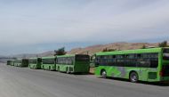 Buses waiting to take members of the opposition evacuated from the rebel-held city of Douma in the Ghouta region, at the Wafidin crossing on the outskirts of the Syrian capital Damascus on April 1, 2018.  SANA
