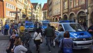 People walk past Police cars in Muenster, western Germany where several people were killed and injured when a car ploughed into pedestrians on April 7, 2018. - Germany OUT / AFP