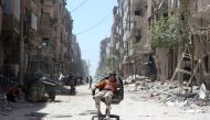 A boy sits on a chair along a damaged street at the city of Douma in Damascus, Syria April 16, 2018. REUTERS/Ali Hashisho