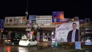 People drive under a bridge in the northern city of Mosul on April 14, 2018, bearing the campaign posters for candidates in the upcoming parliamentary elections. / AFP / Zaid al-Obeidi