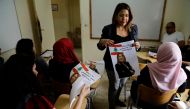 Palestinian parliamentary candidate Manal Kortam (C) explains to a classroom why she has nominated herself for a seat that does not exist in next month's elections at the Mar Elias Palestinian refugee camp in Beirut on April 26, 2018.  AFP / JOSEPH EID

