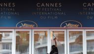 A staff member cleans the doors of the festival's palace on May 8, 2018 ahead of the opening of the 71st edition of the Cannes Film Festival in Cannes, southern France. / AFP / LOIC VENANCE