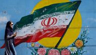 An Iranian woman walks past a mural of the Iranian flag in the capital Tehran on October 14, 2017 (AFP) 