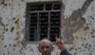An Iraqi voter shows his ink-stained index finger in front of a damaged wall in western Mosul's Zanjili neighbourhood on May 12, 2018, still partially in ruins from the devastating months-long fight to oust the Islamic State (IS) group.   AFP / AHMAD AL-R