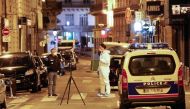A forensic officer (R) and a French policeman (L) stand next to a numbered reference index pad and a camera on a tripod on Saint Augustin street in Paris after one person was killed and several injured by a man armed with a knife, who was shot dead by pol
