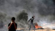A Palestinian man uses a slingshot during clashes with Israeli forces near the border between the Gaza strip and Israel east of Gaza City on May 14, 2018, as Palestinians protest over the inauguration of the US embassy following its controversial move to 