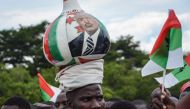 A supporter of Burundi’s ruling CNDD-FDD party, balances a gourd on his head with the image of the Burundian President Pierre Nkurunziza, during a rally three days prior to a referendum on a controversial constitutional reform on May 14, 2018 in Bujumbura