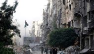 Syrian government forces walk down a destroyed street in the Palestinian camp of Yarmuk on the southern outskirts of Damascus on May 21, 2018. AFP / LOUAI BESHARA