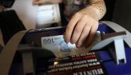 An employee of a foreign exchange office counts and checks Turkish lira banknotes with a machine in the centre of Ankara on May 25, 2018. / AFP / ADEM ALTAN