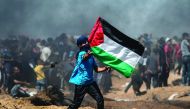 A Palestinian protestor waves his national flag during a demonstration along the border with Israel east of Jabalia in the central Gaza Strip on June 8, 2018.  AFP / Mohammed Abed