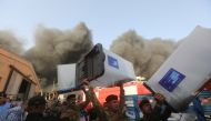 Security forces carry ballot boxes as smoke rises from a storage site in Baghdad, housing the boxes from Iraq's May parliamentary election, Iraq June 10, 2018. Reuters