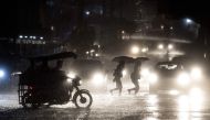 People cross a road during heavy rain caused by Typhoon Maliksi in Manila on June 10, 2018. AFP / Noel Celis