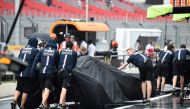 Technicians put rain covers over the cars of Force India's drivers during a heavy rain shower during the third practice session at the Circuit Paul Ricard in Le Castellet, southern France, on June 23, 2018, ahead of the Formula One Grand Prix de France. A