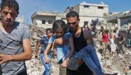 A man carries a child rescued from rubble after Syrian regime and Russian air strikes in the rebel-held town of Nawa, about 30 kilometres north of Daraa in southern Syria on June 26, 2018.  AFP / Ahmad al-Msalam
