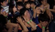 Japanese soccer fans react while watching Japan's loss to Belgium in a public viewing of the 2018 Russia World Cup round of 16 football match in Tokyo early July 3, 2018. / AFP / Toshifumi Kitamura 