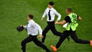 Member of security runs after strikers on the football pitch during the Russia 2018 World Cup final football match between France and Croatia at the Luzhniki Stadium in Moscow on July 15, 2018. AFP / Alexander Nemenov

